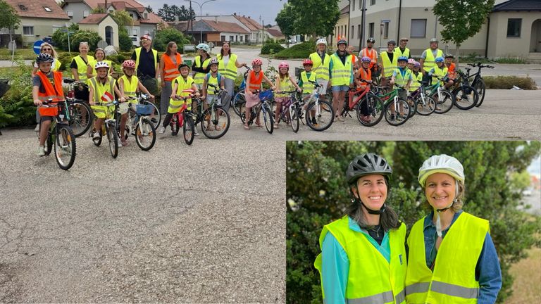 Eine Gruppe von Kindern und Erwachsenen in Sicherheitswesten und Helmen posiert mit ihren Fahrrädern auf einem Stadtplatz.