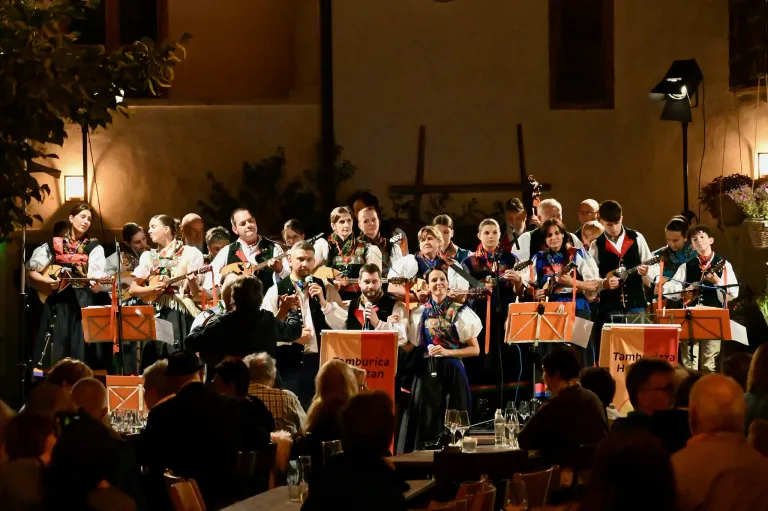 Eine Gruppe Musiker in traditioneller Kleidung spielt auf der Bühne mit Gitarren und singt vor einem Publikum.