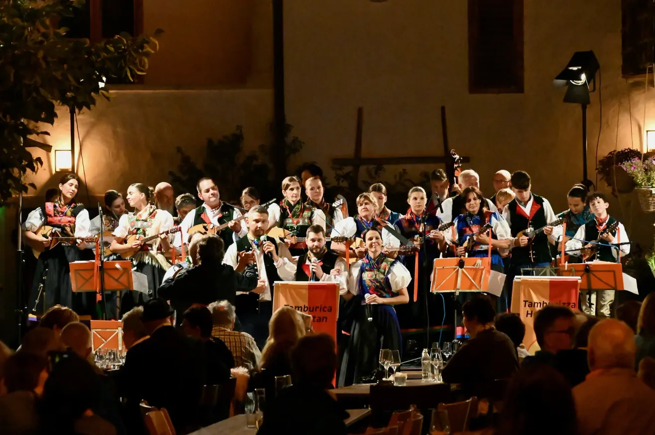 Eine Gruppe Musiker in traditioneller Kleidung spielt auf der Bühne mit Gitarren und singt vor einem Publikum.