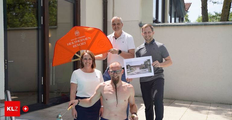 Vier Personen stehen vor einem Gebäude, zwei Männer und zwei Frauen. Ein Mann hält eine Flagge und ein Bild, ein anderer Mann hält einen Golfschläger und die Frauen halten eine Flagge und einen Golfschläger.