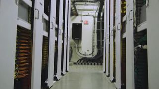 Ein Innenansicht eines Rechenzentrums mit mehreren Server-Racks und Kabeln. Der Boden ist sauber und gut beleuchtet.