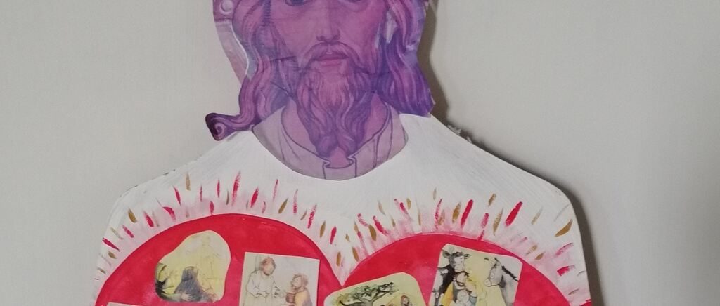 A colorful paper cutout of Jesus Christ with a purple head and beard, surrounded by smaller images of biblical scenes, mounted on a white background.