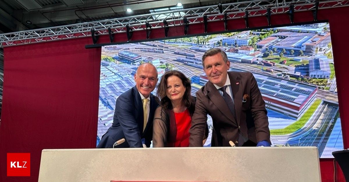 Three people in formal attire stand behind a podium, smiling for a photo with a large screen showing a cityscape in the background.