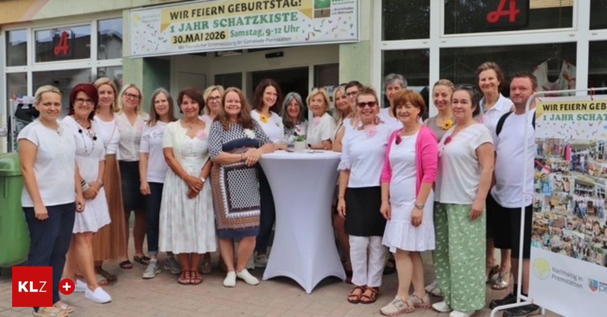 A group of women in white dresses and accessories stand in front of a building, smiling for a photo. A banner above reads 'Wir feiern Geburtstag' with a date of May 30, 2026.
