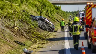 A car has crashed into the guardrail on the side of the road, with emergency personnel attending to the scene.