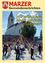 Eine große Gruppe von Menschen versammelt sich um einen Maibaum vor einer Kirche, während eine Menge zuschaut. Das Bild hat einen gelben Rand und enthält Text auf Deutsch.