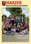 Eine Gruppe von Kindern und Erwachsenen posiert für ein Foto im Freien an einem sonnigen Tag. Das Foto hat einen gelben Rand und Textüberlagerung.