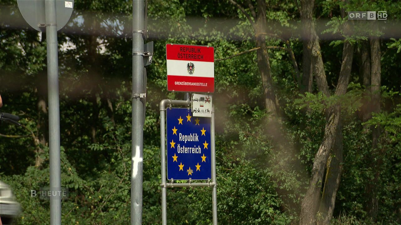 Ein blau-gelbes Schild mit dem Text 'Republik Osterreich' und der Flagge der Europäischen Union, montiert an einem Pfosten mit einem roten Schild darüber.