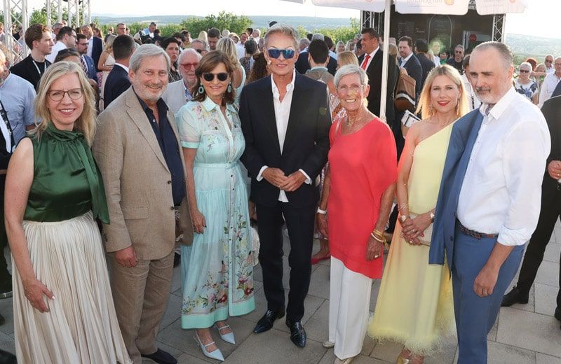 Eine Gruppe von Menschen in formeller Kleidung posiert für ein Foto bei einer Outdoor-Veranstaltung.