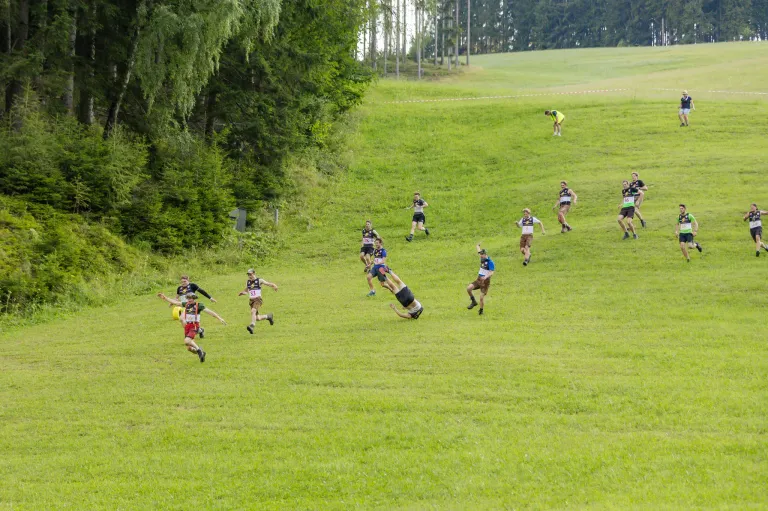 Eine Gruppe von Läufern nimmt an einem Rennen auf einem Grasfeld teil, einige fallen, während andere laufen.