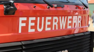 A close-up view of a red fire truck with the word 'FEUERWEHR' in white letters on the front. Below, the word 'IVECO' is visible on the bumper.