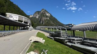 A clear day with a mountain backdrop, featuring an empty road, a metal structure, and a grassy area.