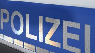 A close-up view of the word 'POLIZEI' in bold, silver letters on a blue background. The letters have a metallic texture and are slightly reflective.