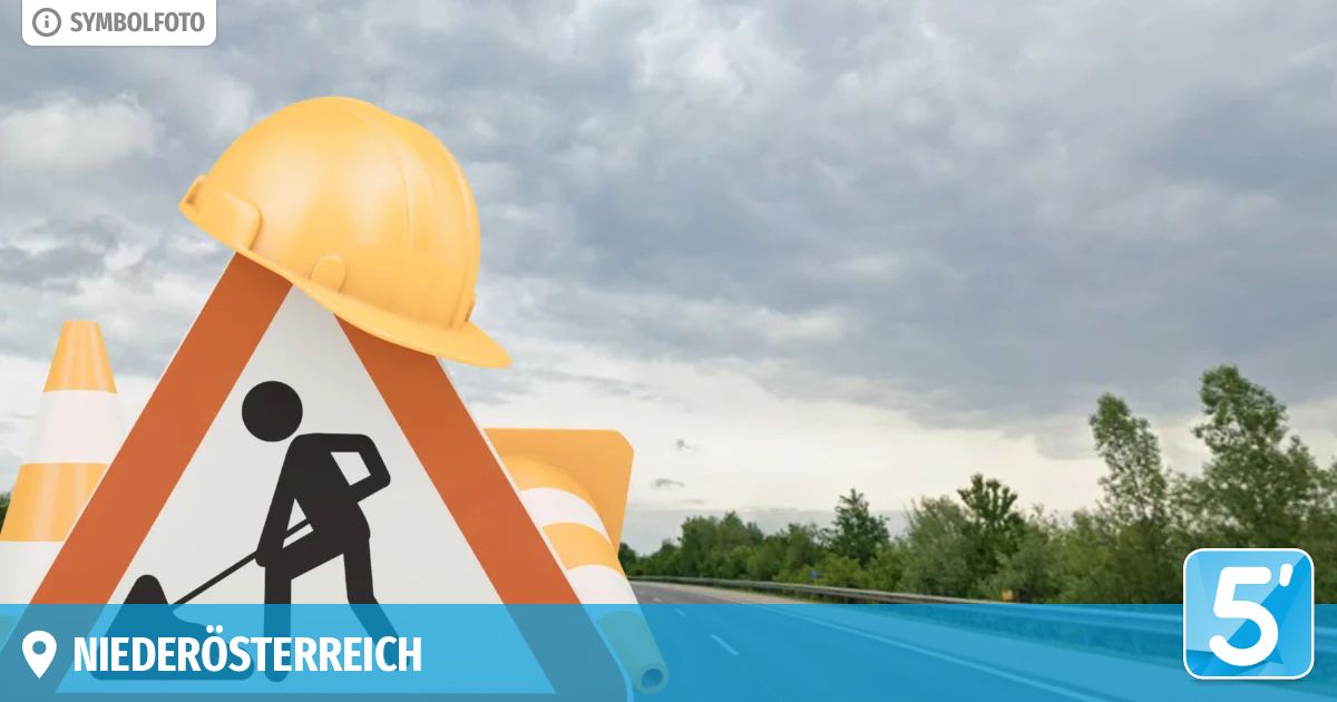 A road sign with a construction worker silhouette and a yellow hard hat on top, against a cloudy sky and a blurred road.
