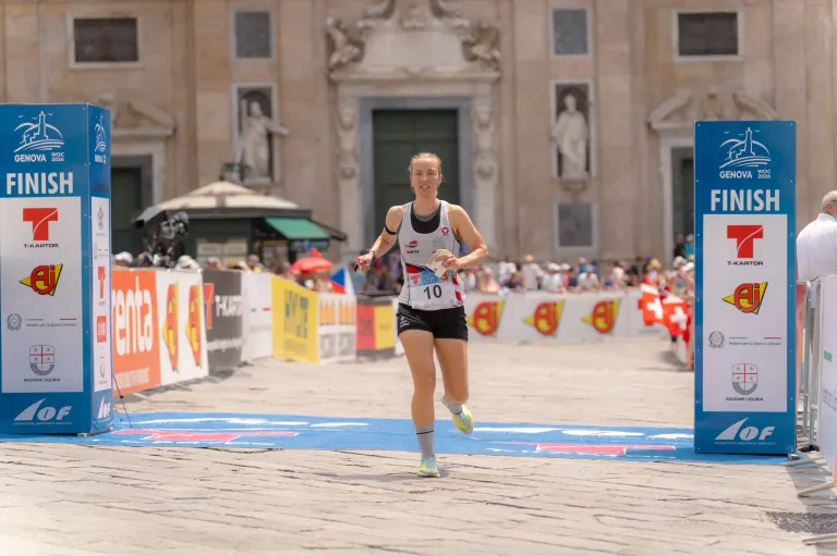 A woman runner with the number 10 on her shirt is running in a marathon in front of a historic building.