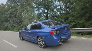 Ein blauer BMW 3er-Kombi mit beschädigtem Heck steht am Straßenrand.