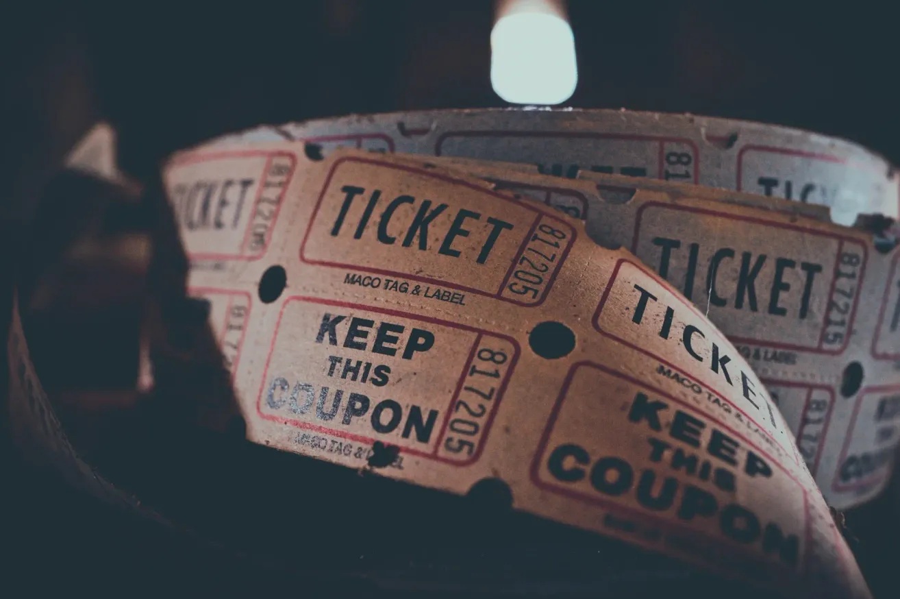 Ein Nahaufnahme eines zerrissenen Tickets mit den Worten 'KEEP THIS COUPON' und 'TICKET' sichtbar, zusammen mit einem Datumsstempel '502218'. Der Hintergrund ist unscharf.