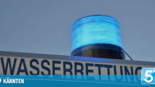 Ein blaues Notfalllicht auf einem Schild, das 'ASSERRETTUNG' in weißen Buchstaben auf blauem Hintergrund steht.