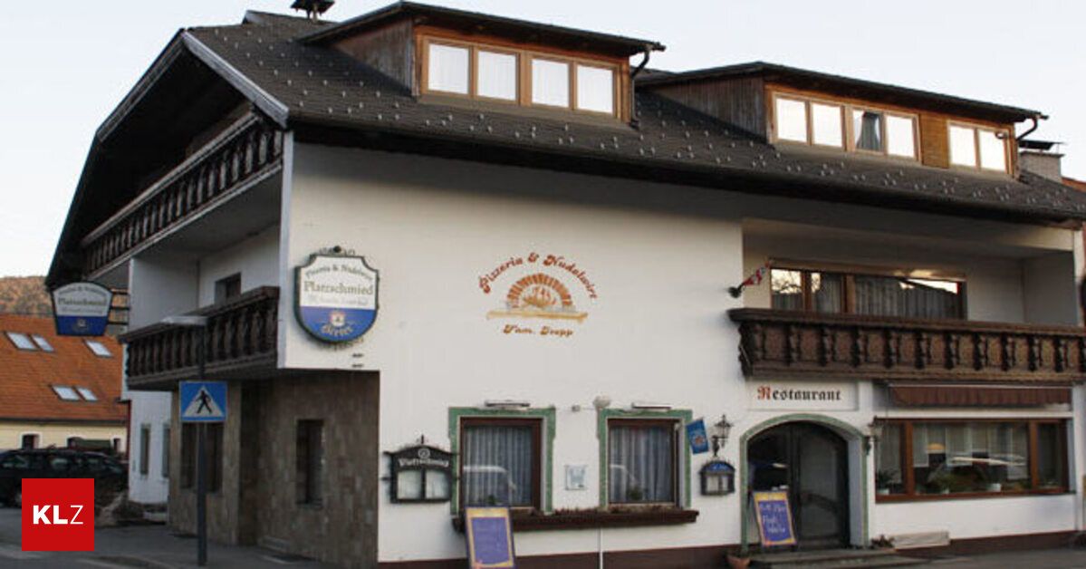 Ein traditionelles europäisches Gebäude mit einem Restaurant-Schild, einem blauen kreisförmigen Schild und einem Balkon mit Holzgittern.