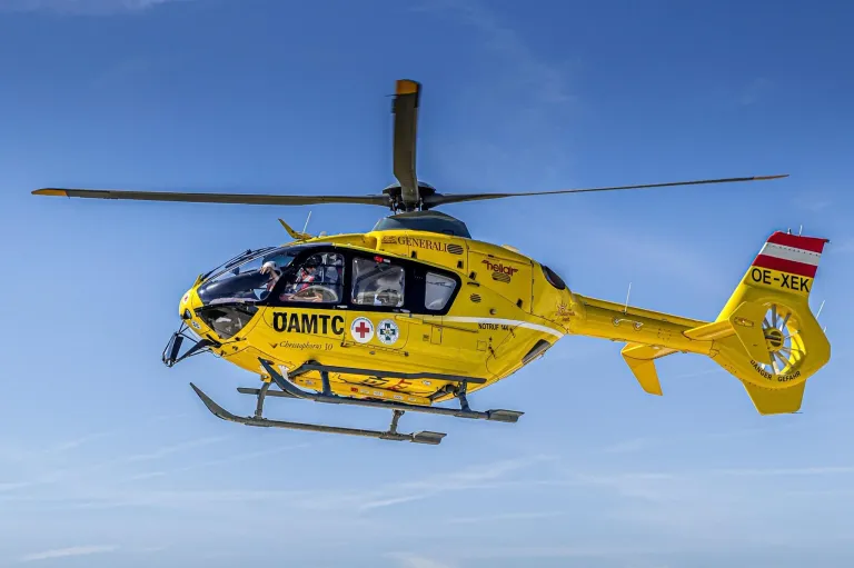 A yellow medical helicopter with the text 'OAMTC' and a red cross on the side is flying in the sky.