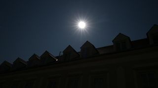Ein heller Sonnenschein scheint über die Dächer eines Gebäudes in der Nacht.