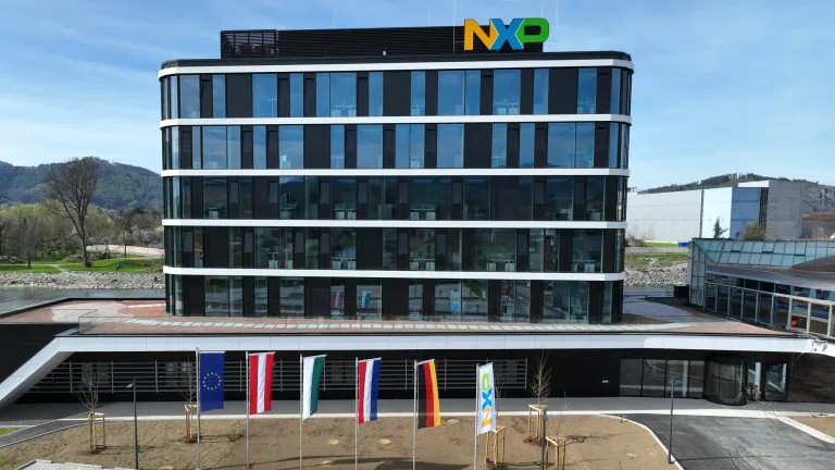 NXP Semiconductors' modernes Bürogebäude mit Glasfassaden, vor dem Flaggen verschiedener Länder stehen.