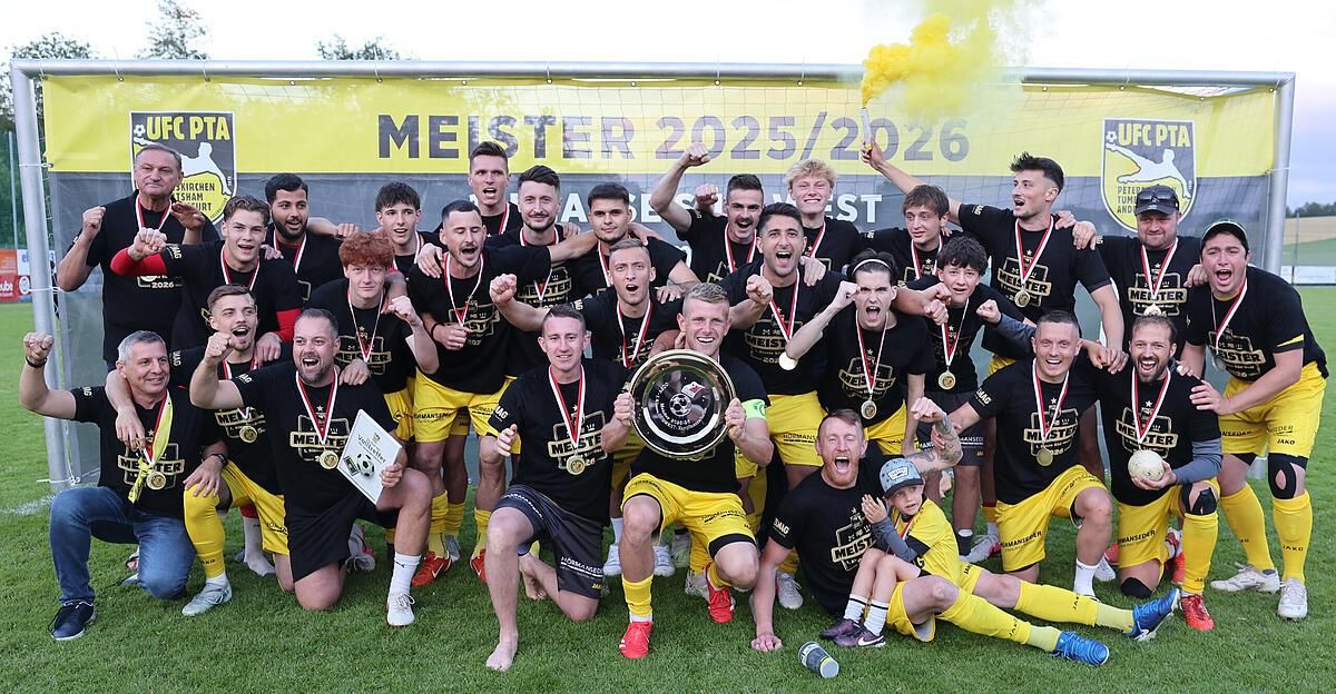 A soccer team celebrates their victory with medals and a trophy. The team is wearing black and yellow uniforms. The background features a yellow banner with the text 'MEISTER 2025/2026'.