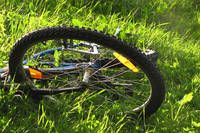 Ein Fahrradrad liegt mit dem Vorderrad nach oben auf dem Gras. Das Fahrrad scheint beschädigt zu sein.