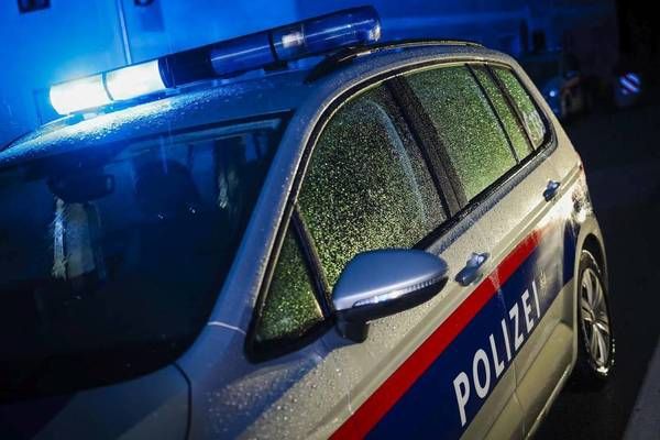 Ein Polizeiauto mit eingeschalteten Lichtern steht nachts am Straßenrand.