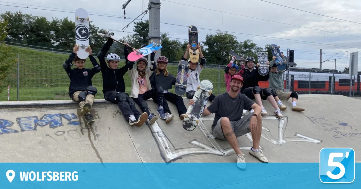 Eine Gruppe junger Skateboarder posiert mit ihren Boards auf einer Skatepark-Rampe. Sie tragen alle Helme und einige haben Knieschützer an.