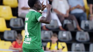 Ein Fußballspieler in einem grünen Trikot mit der Nummer 14 feiert ein Tor vor einer verschwommenen Menge.