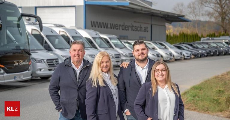 Vier Personen stehen vor einem Gebäude mit einem Schild, auf dem www.werderitsch.at steht. Sie lächeln alle und scheinen für ein Foto zu posieren. Dahinter sind mehrere Autos in einer Reihe geparkt.
