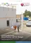 Drei Männer stehen vor einem teilweise errichteten Gebäude, einer trägt ein weißes Hemd und die anderen zwei orange und graue Hemden. Hinter ihnen ist ein großer Pfeiler zu sehen, und im Hintergrund befinden sich Baumaterialien und ein Lieferwagen.