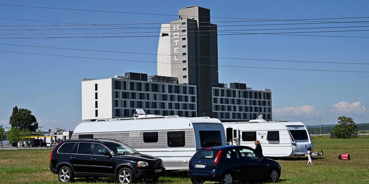 Ein großes Hotelgebäude mit dem Wort Hotel oben, vor dem mehrere Autos und Wohnwagen geparkt sind.