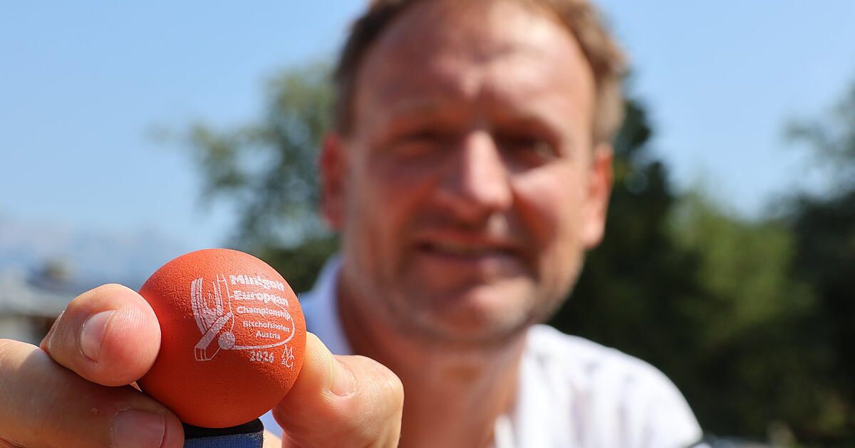Ein Mann hält einen roten Ball mit der Aufschrift 'Mittagsball European Championship' und 'Bischalshohen Austria 2024'. Er trägt ein weißes Poloshirt.