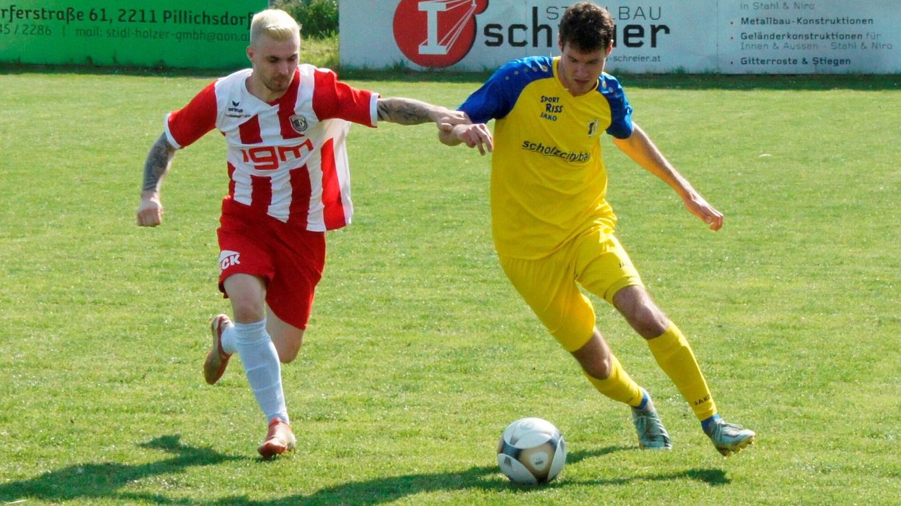 Zwei Fußballspieler in Aktion auf einem Feld, einer in Rot und Weiß, der andere in Gelb, beide versuchen den Ball zu kontrollieren.