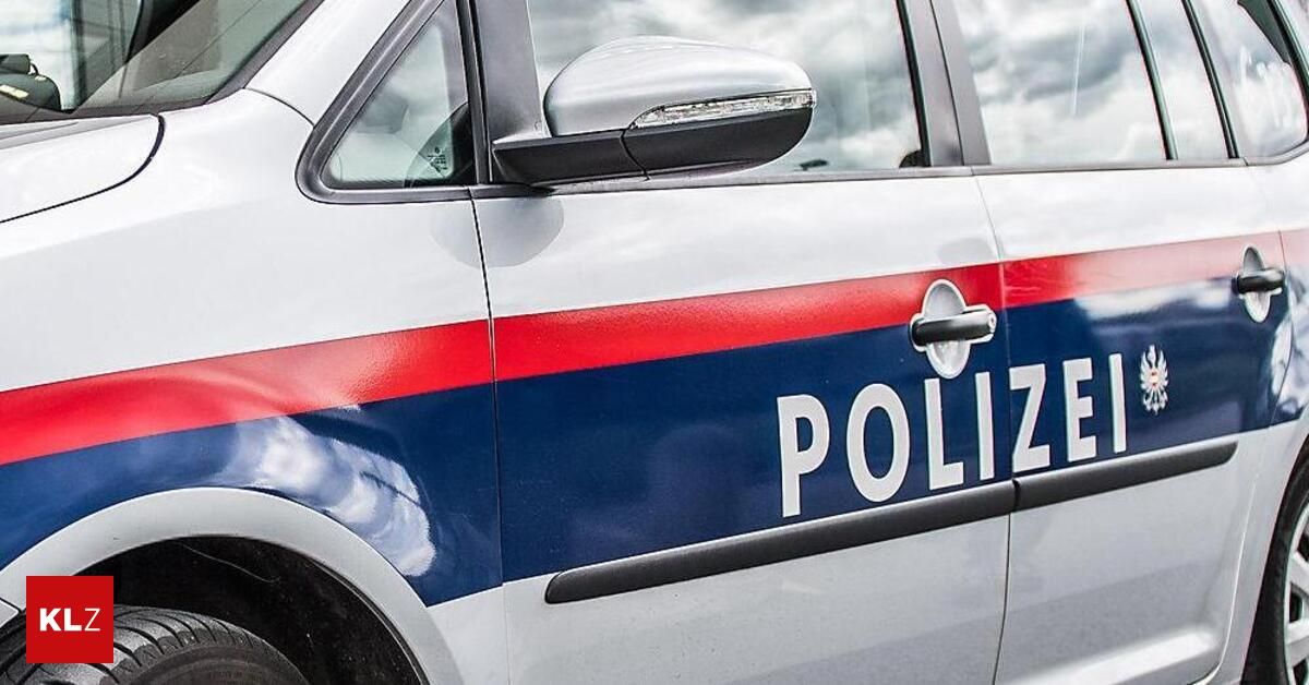 Ein Nahaufnahme von der Seite eines Polizeiwagens mit roten und blauen Streifen und dem Wort 'POLIZEI' in weiß. Der Seitenspiegel des Autos ist silber.