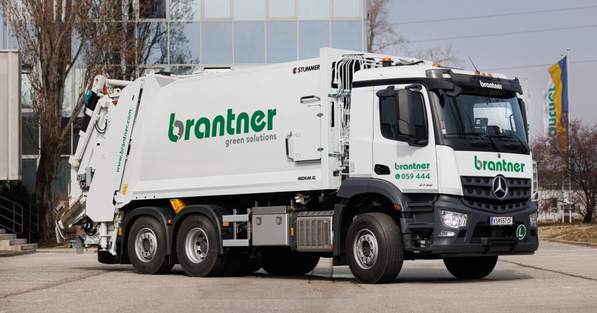 Ein weißer brantner Müllwagen mit grünen Akzenten vor einem Gebäude geparkt. Der Lkw hat den Text brantner green solutions an der Seite.