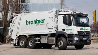 Ein weißer brantner Müllwagen mit grünen Akzenten vor einem Gebäude geparkt. Der Lkw hat den Text brantner green solutions an der Seite.