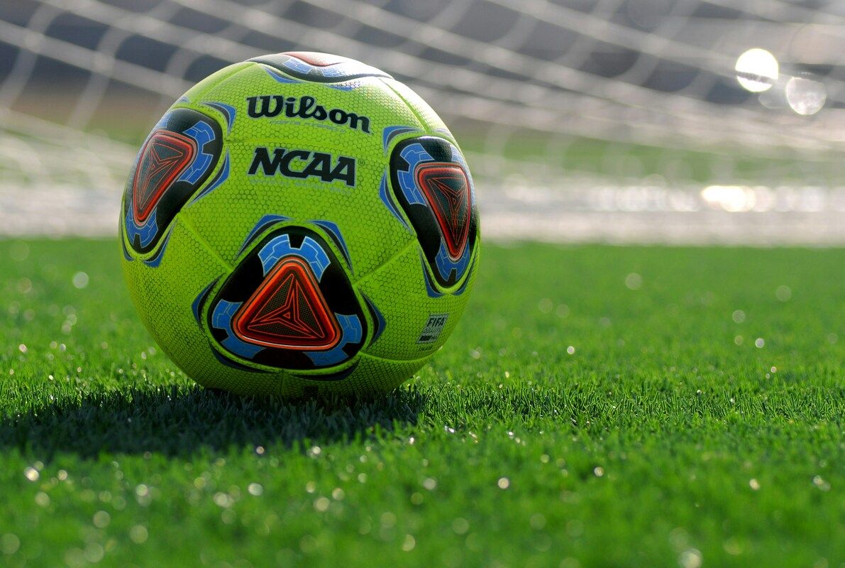 Ein Nahaufnahme eines grünen Fußballs mit Wilson- und NCAA-Logos, der auf einem grünen Feld ruht.