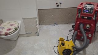 A construction site with unfinished walls and a yellow blower on the floor.