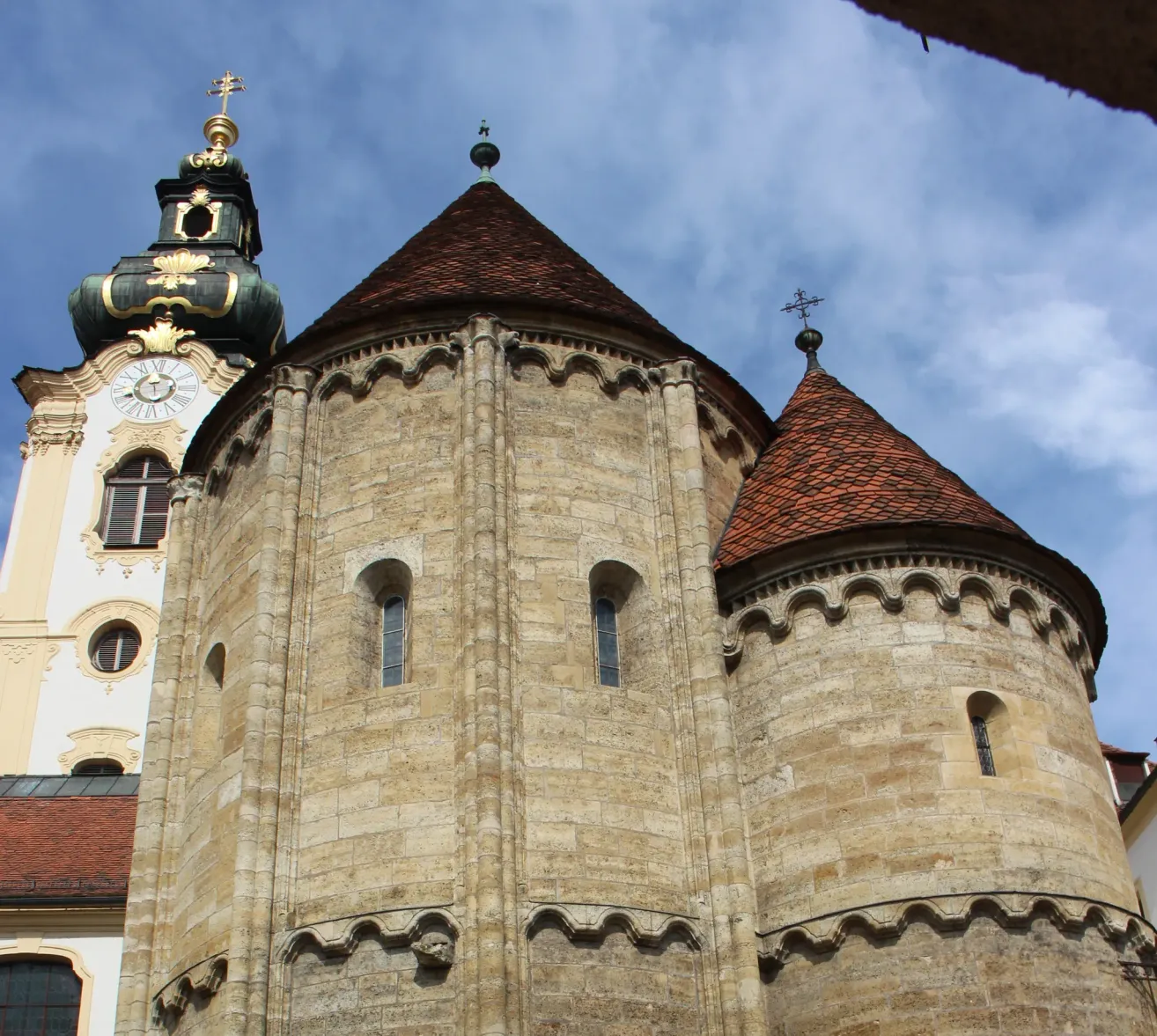 A close-up view of a medieval church with two towers and a clock on one tower. The towers have pointed roofs and decorative stonework.