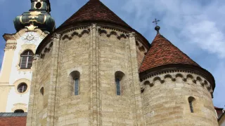 A close-up view of a medieval church with two towers and a clock on one tower. The towers have pointed roofs and decorative stonework.
