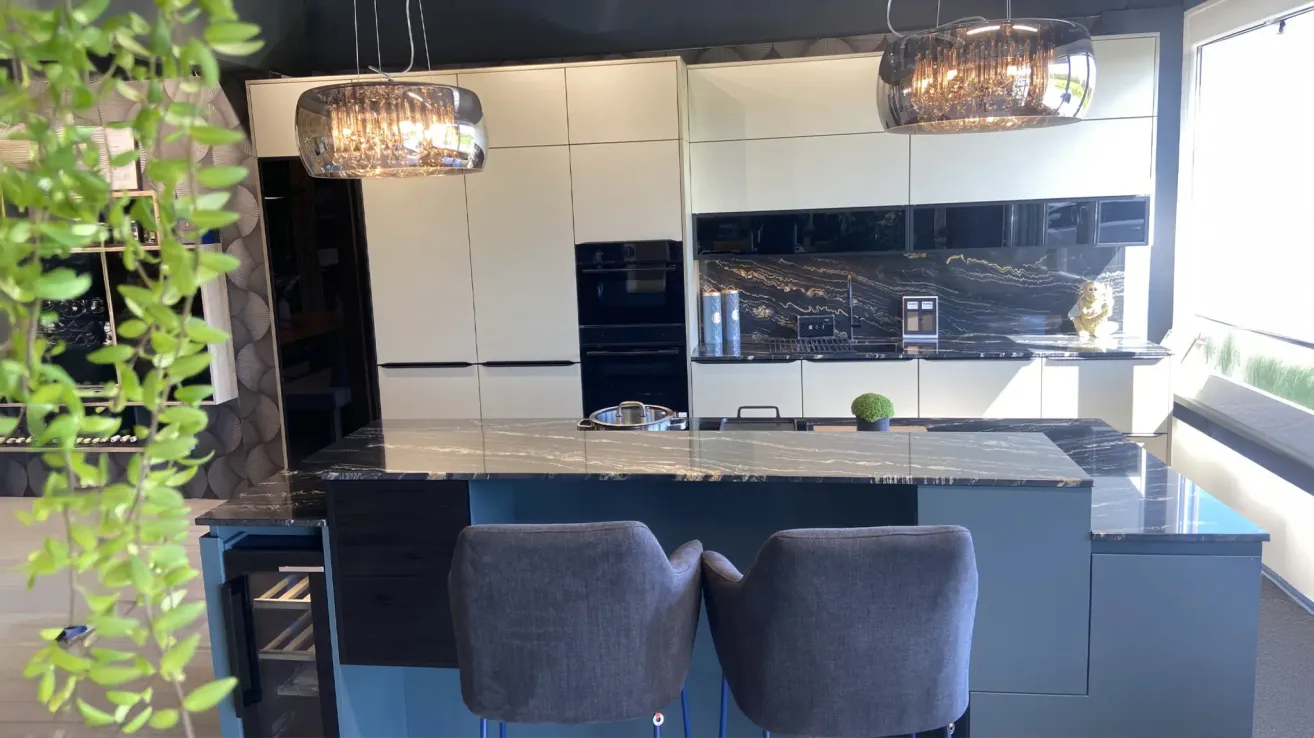 A modern kitchen with white cabinets, marble countertops, and two gray bar stools in front of a black oven.