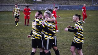 Fußballspieler in gelben und schwarzen Trikots feiern auf einem Feld mit unscharfem Hintergrund.