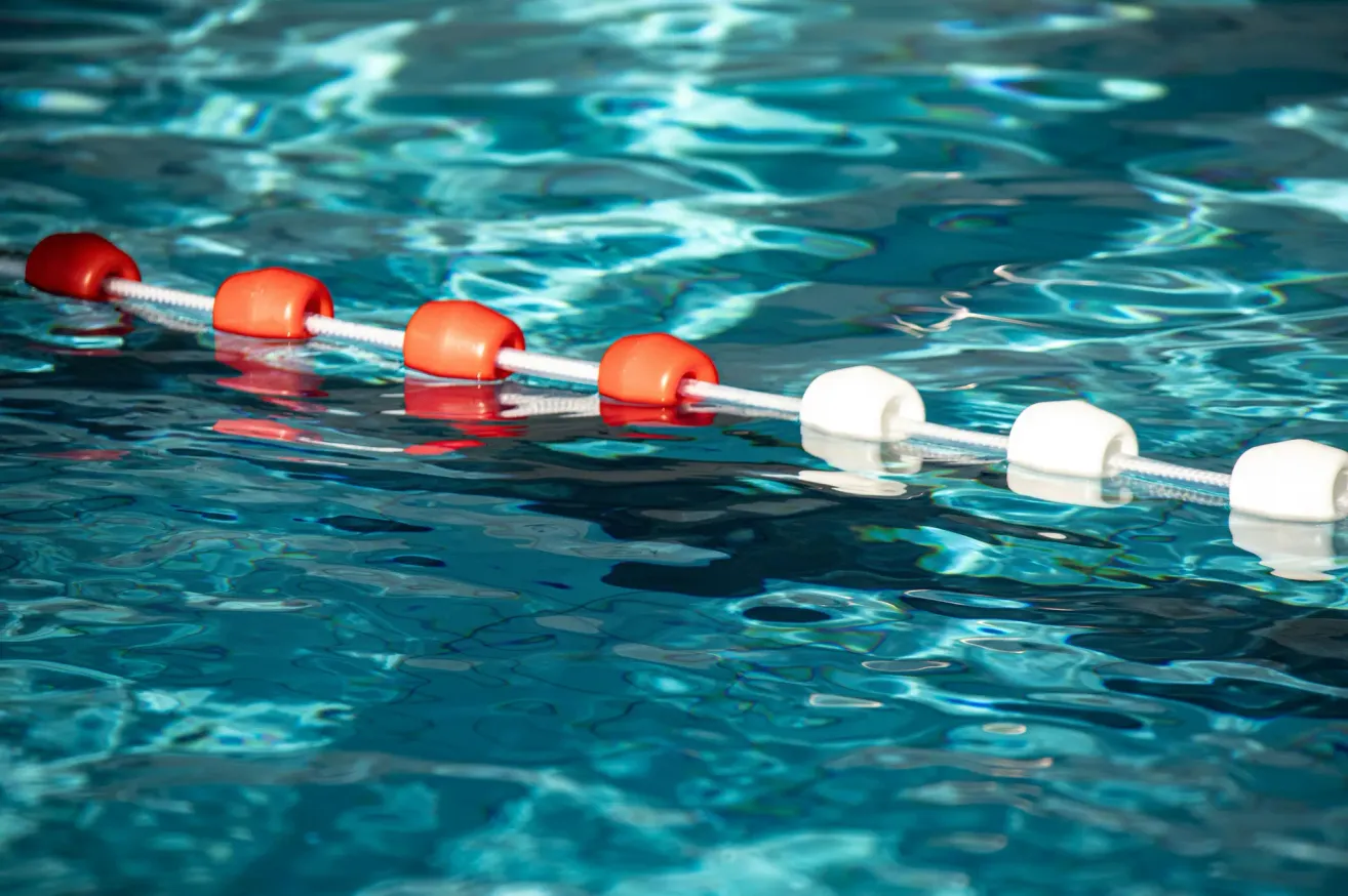 A close-up view of a pool with a white rope and orange floats floating on the water surface.