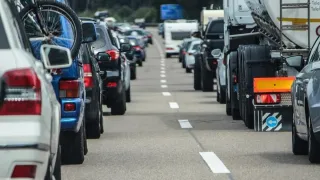 Ein Stau mit mehreren Fahrzeugen, darunter Autos und LKWs, auf einer Straße mit weißen Markierungen.