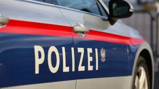 Ein Nahaufnahme eines Polizeiwagens mit dem Wort 'POLIZEI' und einem Logo auf der Seite. Das Auto ist blau und weiß mit roten Streifen.