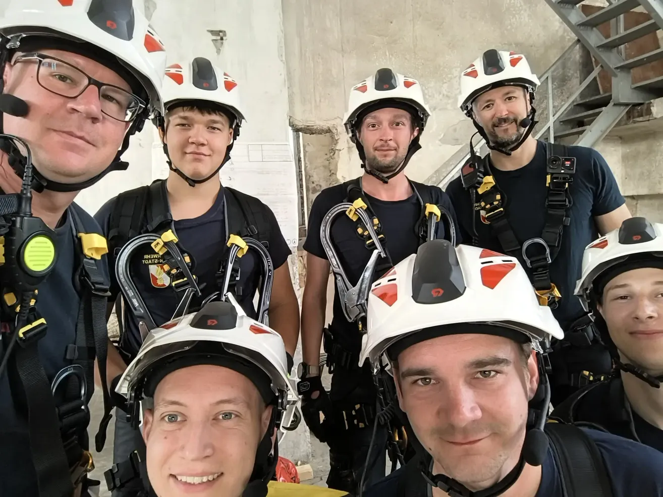 Eine Gruppe von Männern in Helmen und Gurten posiert für ein Foto in einer Innenumgebung.