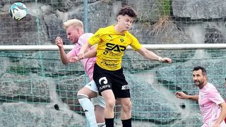 Zwei Fußballspieler in Aktion, einer in einem gelben Trikot mit 'SAP' und der andere in einem rosa Trikot, beide in der Luft, wahrscheinlich in einem Wettkampf.